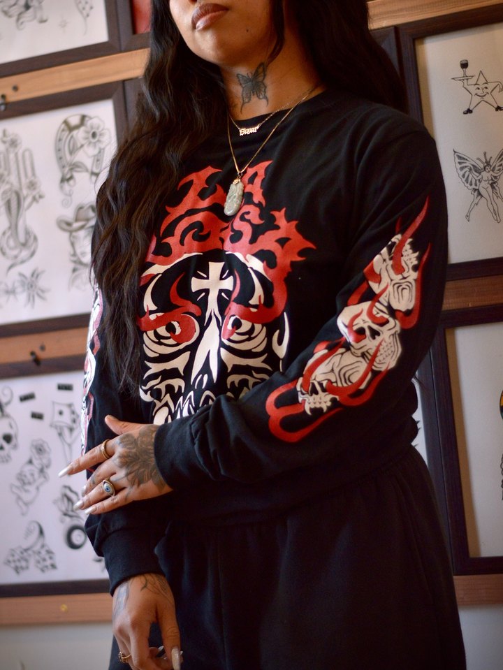 A black La Rosa long sleeve with a red and white rose, cross and skull print, worn in front of the flash wall.