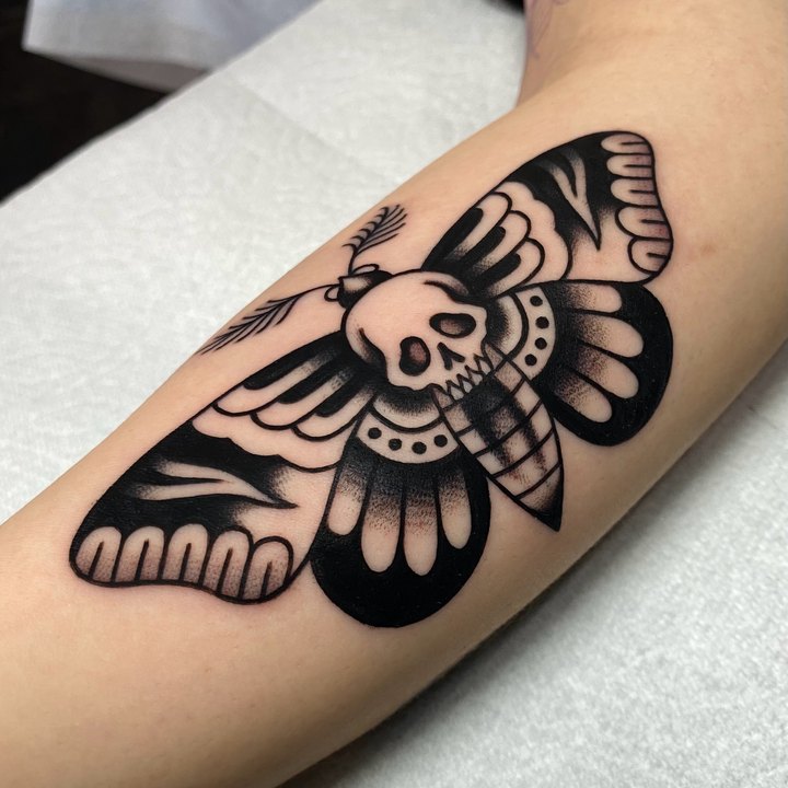 A bold blackwork death's-head moth tattooed on an inner forearm.